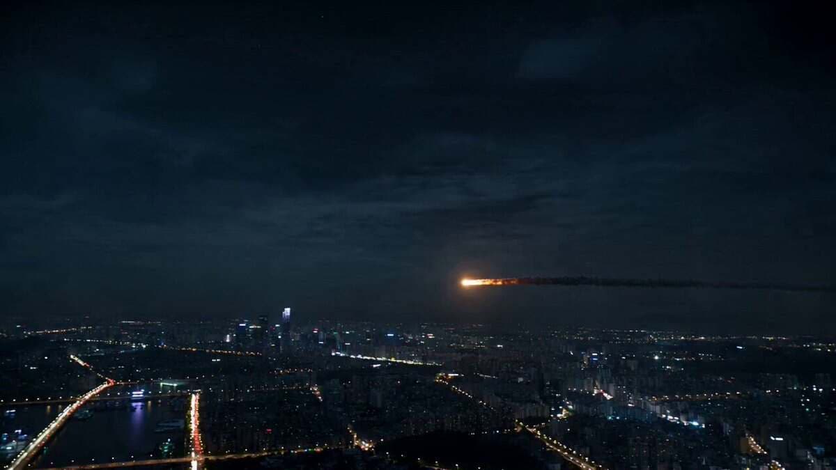 A glowing asteroid enters the atmosphere above a sprawlin...